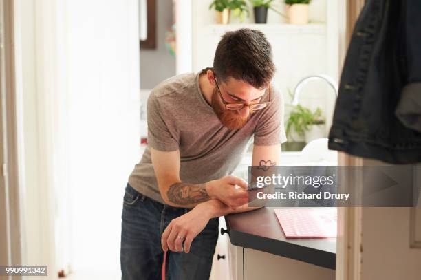 young hipster man using a smart phone in his kitchen - hipster in a kitchen stock-fotos und bilder
