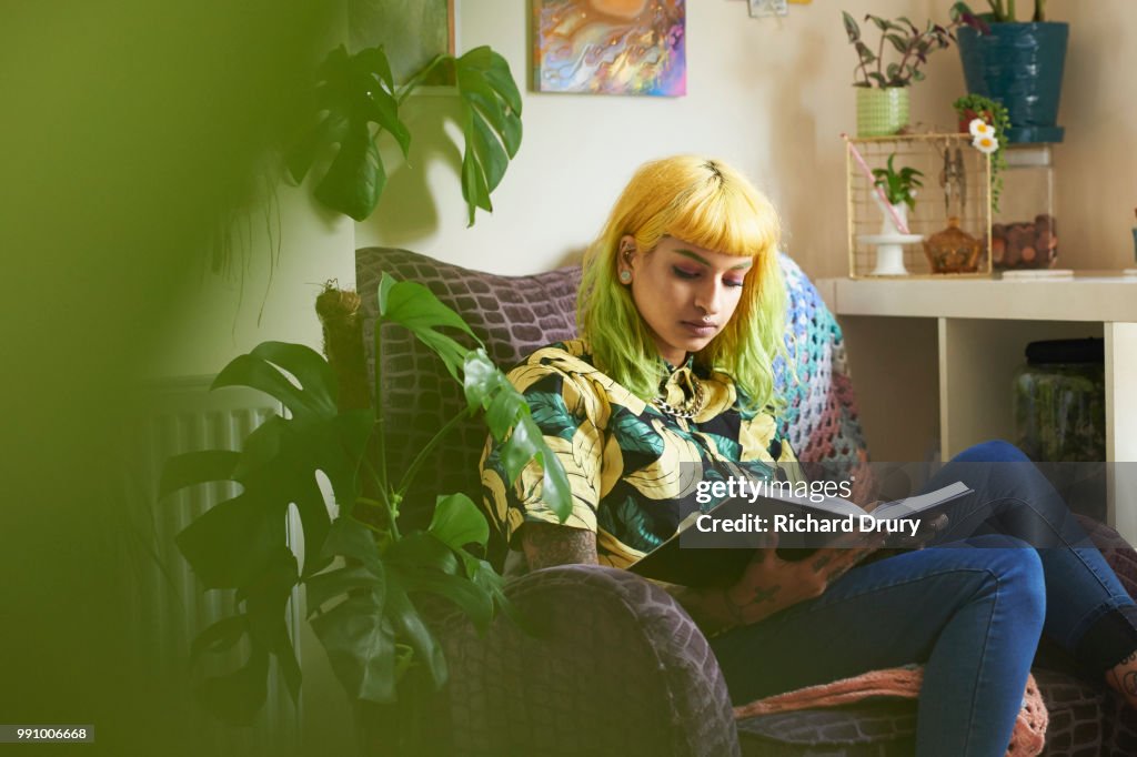 Young hipster woman reading a book in her living room