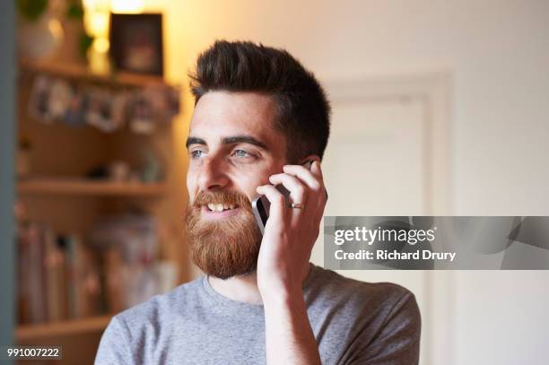 hipster man using a smart phone in his living room - richard drury stock pictures, royalty-free photos & images