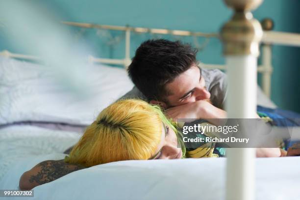 young hipster couple lying on their bed together - richard drury stock pictures, royalty-free photos & images