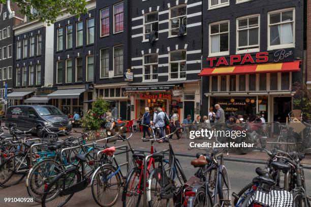 street in central amsterdam, bicyles parked on the side, shops and pedetrians along thee road. - thee stock pictures, royalty-free photos & images