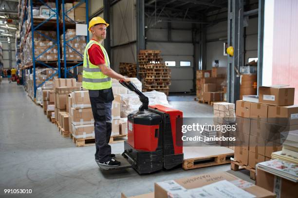 warehouse worker walking among shelves with handcart - pallet jack stock pictures, royalty-free photos & images