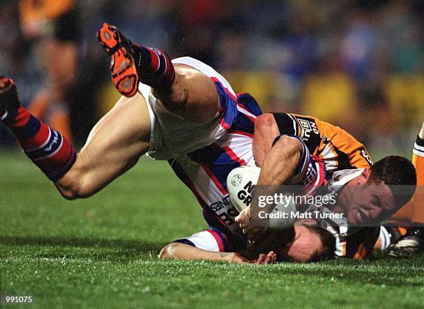 Adam MacDougall of the Knights gets tackled by Luke O''Donnell of the Tigers during the Round 23 NRL match at Campbelltown Stadium, Sydney,...