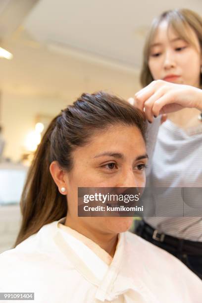 latin woman having hair done - kumikomini stock pictures, royalty-free photos & images