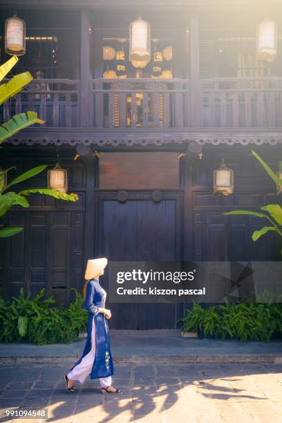 vietnamese woman with traditional clothes and conical hat visiting the old town of hoi an in vietnam , southeast asia - hoi an stockfoto's en -beelden
