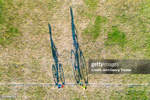 long shadows of two boys cycling - long grass stockfoto's en -beelden