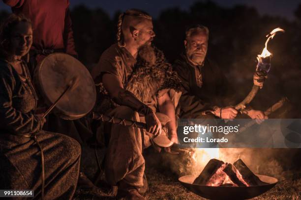 une horde de guerriers vikings s’asseoir et parler autour d’un feu dans la nuit - sasseoir photos et images de collection