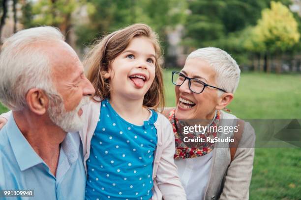 grandparents looking at their granddaughter sticking out tongue - glases group nature stock pictures, royalty-free photos & images