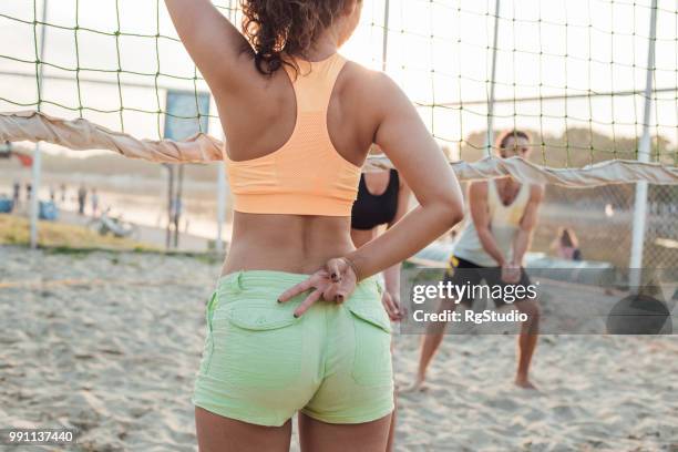 sportlerin mit zwei fingern hinter ihrem rücken - womens beach volleyball stock-fotos und bilder