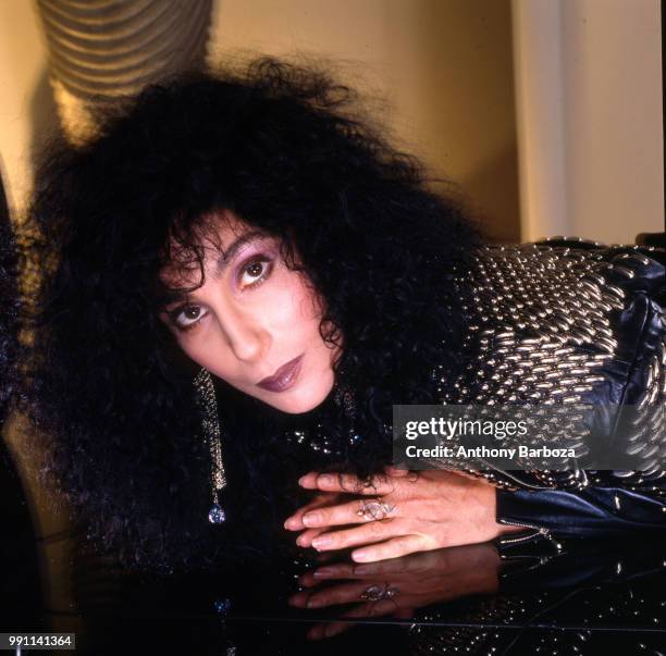 Portrait of American singer and actress Cher as she lies on reflective surface, Los Angeles, California, 1987.