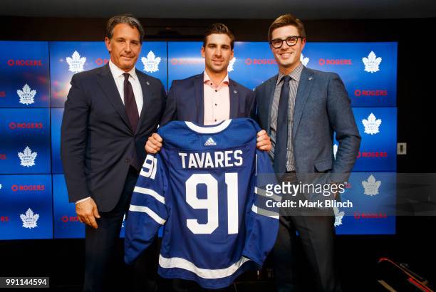 John Tavares of the Toronto Maple Leafs poses with his jersey after signing with the Maple Leafs, beside Kyle Dubas, General Manager of the Toronto...