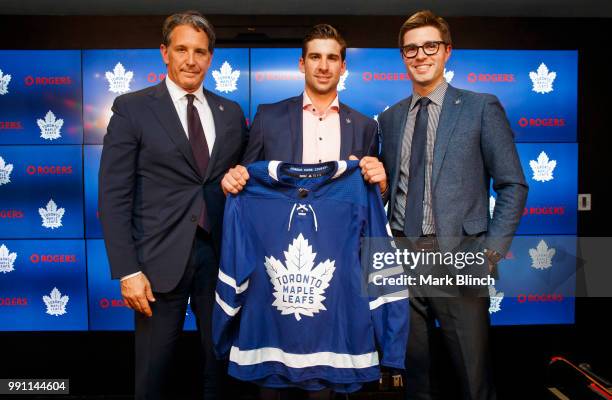 John Tavares of the Toronto Maple Leafs poses with his jersey after signing with the Maple Leafs, beside Kyle Dubas, General Manager of the Toronto...