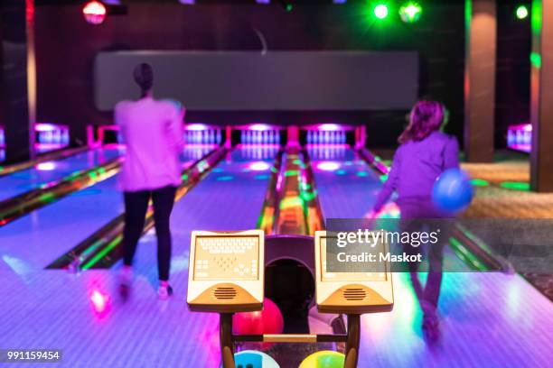 computer monitors against teenage girls throwing balls on parquet floor at bowling alley - bowling alley fotografías e imágenes de stock