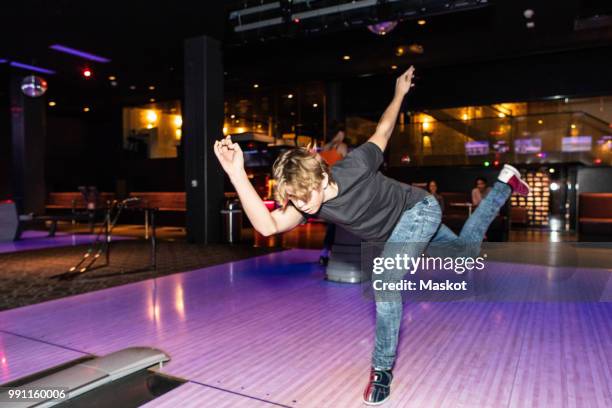 full length of teenage boy bowling on parquet floor - bowling alley stock pictures, royalty-free photos & images