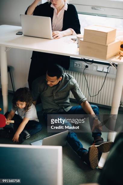 high angle view of father and son sitting with laptop by businesswoman working at creative office - lower employee engagement stock pictures, royalty-free photos & images
