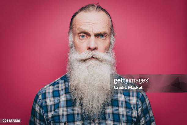 portrait of confident senior man with long white beard over pink background - vollbart stock-fotos und bilder