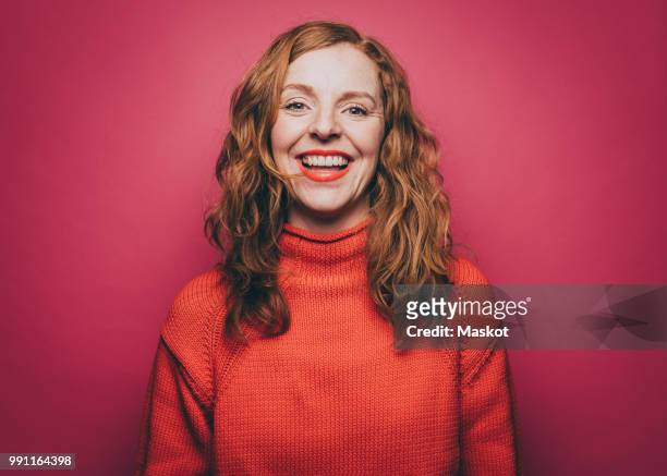portrait of smiling woman in orange top against pink background - fashion orange colour stock pictures, royalty-free photos & images