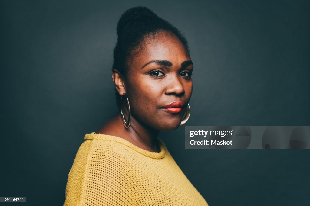 Portrait of confident mid adult woman over gray background