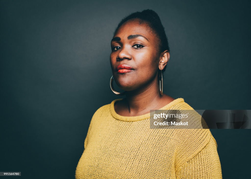 Portrait of confident mid adult woman against gray background