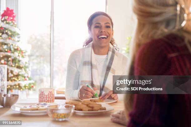amigas, riendo juntos y decorar galletas de navidad - figurita de jengibre fotografías e imágenes de stock