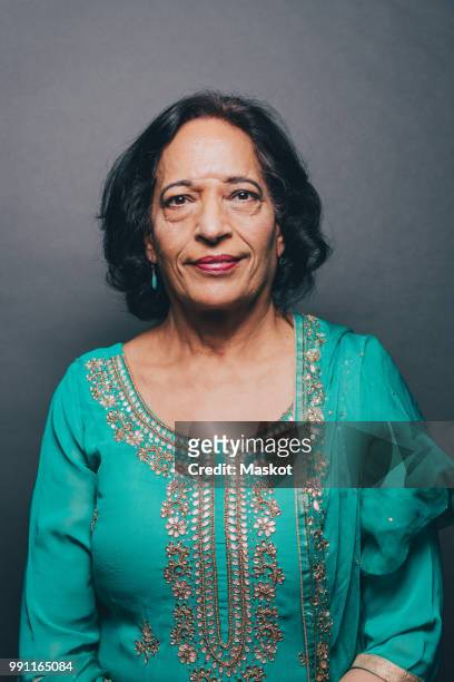 Portrait of confident senior woman wearing salwar kameez on gray background