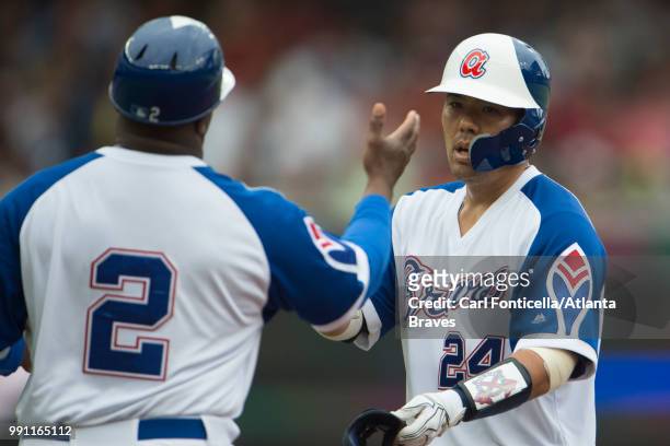 First base coach Eric Young high-fives Kurt Suzuki of the Atlanta Braves after his double against the Baltimore Orioles at SunTrust Park on June 23,...