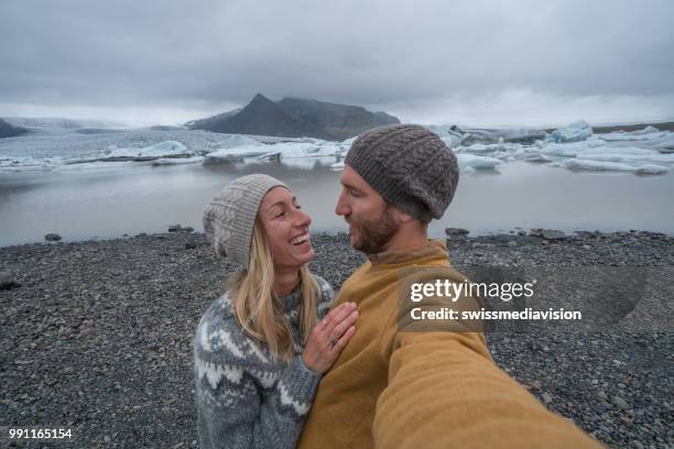 young couple taking selfie with glacier lagoon, icebergs floating on water - south east iceland stock pictures, royalty-free photos & images