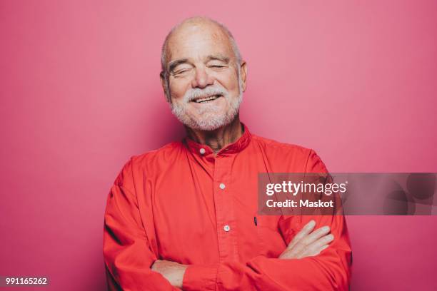 smiling senior man with eyes closed against pink background - man smiling eyes closed stock pictures, royalty-free photos & images