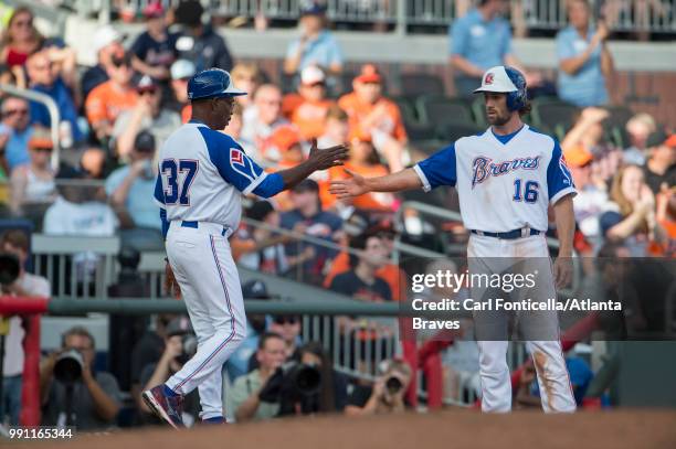 Third base coach Ron Washington high-fives Charlie Culberson of the Atlanta Braves against the Baltimore Orioles at SunTrust Park on June 23, 2018 in...