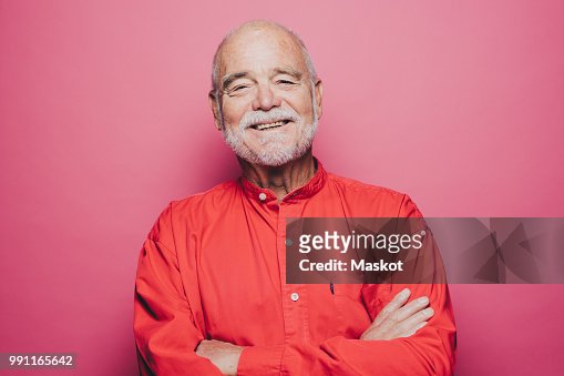 Portrait Of Smiling Senior Man With Arms Crossed Against Pink ...