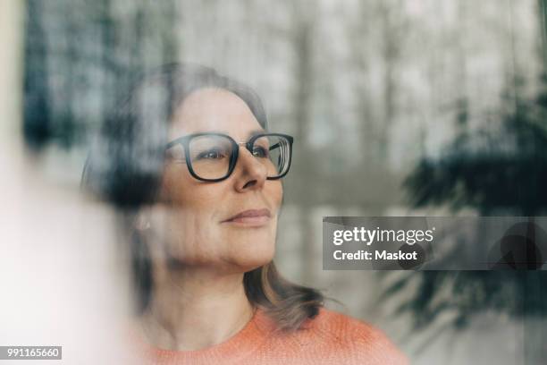 close-up of thoughtful businesswoman wearing eyeglasses seen through window - business casual women stock pictures, royalty-free photos & images