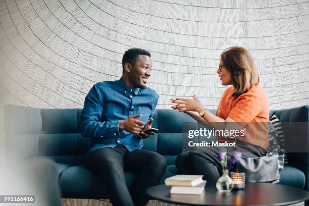 businessman and woman using mobile phones while sitting on couch during conference - business phone meeting bildbanksfoton och bilder