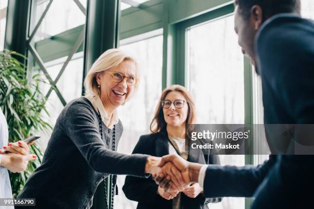 senior businesswoman greeting colleagues during conference - abmachung stock-fotos und bilder