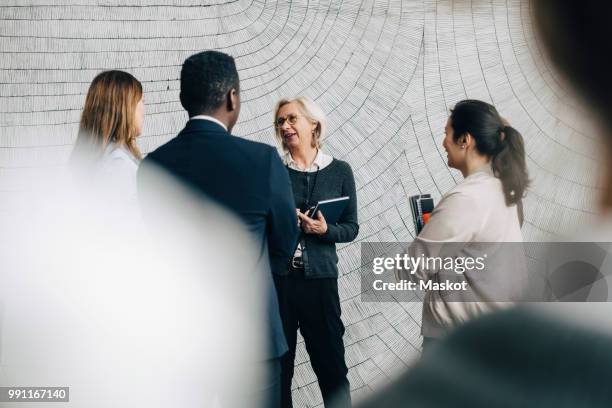 senior businesswoman discussing with male and female coworkers in meeting at office - agenda meeting stock pictures, royalty-free photos & images