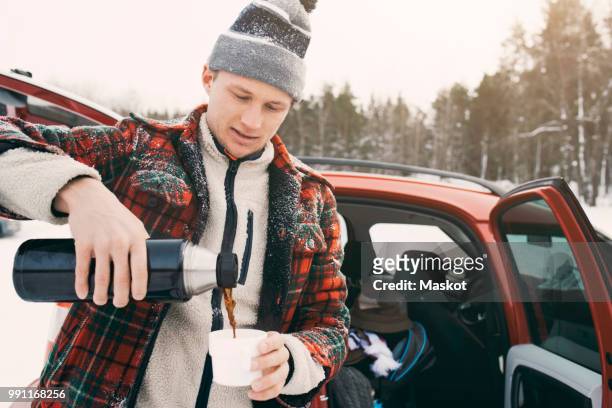 mid adult man pouring coffee from insulated drink container while standing by car - car isolated doors open stock pictures, royalty-free photos & images