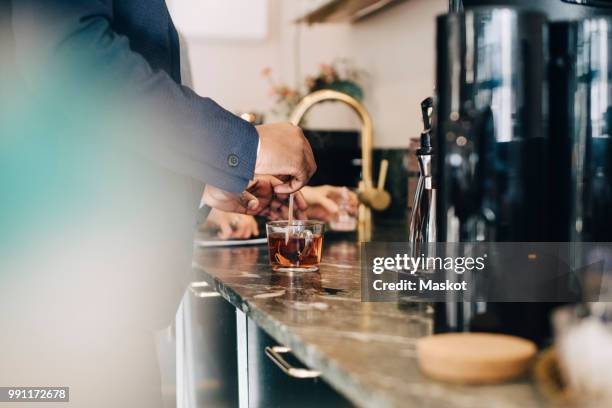 midsection of businessman making tea while standing at kitchen counter in office - making tea stock pictures, royalty-free photos & images