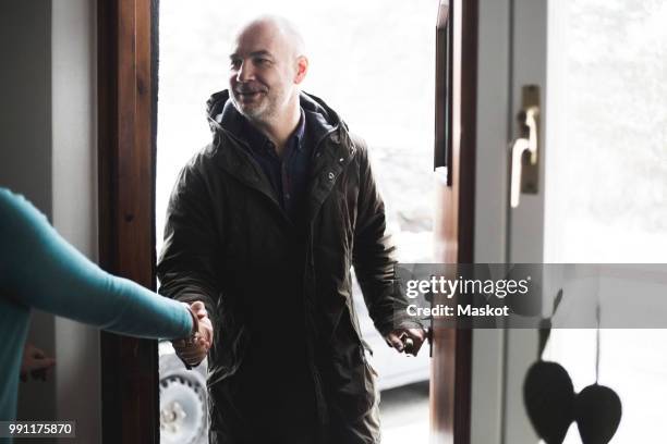 mature man shaking hands with doctor at open doorway - man opening door woman bildbanksfoton och bilder