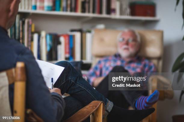 male therapist with senior patient during therapy session - psychiatercouch stock-fotos und bilder