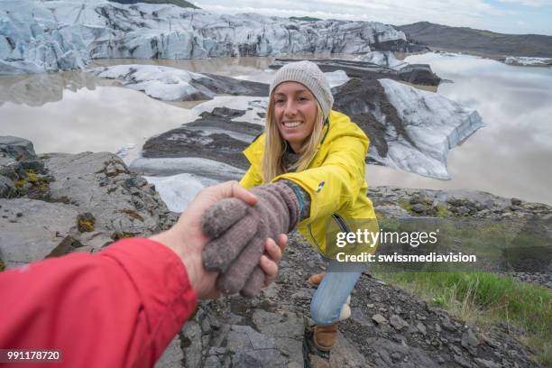 hiker assists teammate to reach glacier top - south east iceland stock pictures, royalty-free photos & images