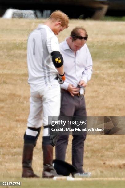 Prince Harry, Duke of Sussex looks on as he has his sunglasses cleaned for him by his polo manager Andrew Tucker during the Audi Polo Challenge at...