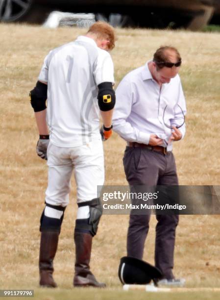 Prince Harry, Duke of Sussex looks on as he has his sunglasses cleaned for him by his polo manager Andrew Tucker during the Audi Polo Challenge at...