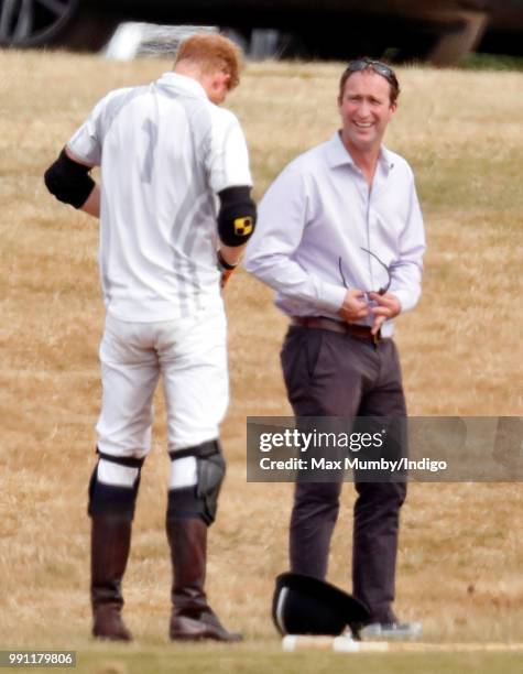 Prince Harry, Duke of Sussex looks on as he has his sunglasses cleaned for him by his polo manager Andrew Tucker during the Audi Polo Challenge at...