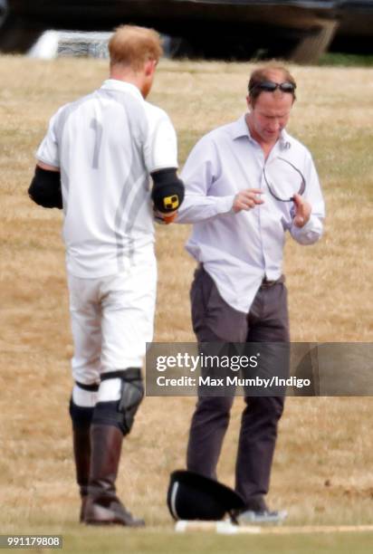 Prince Harry, Duke of Sussex looks on as he has his sunglasses cleaned for him by his polo manager Andrew Tucker during the Audi Polo Challenge at...