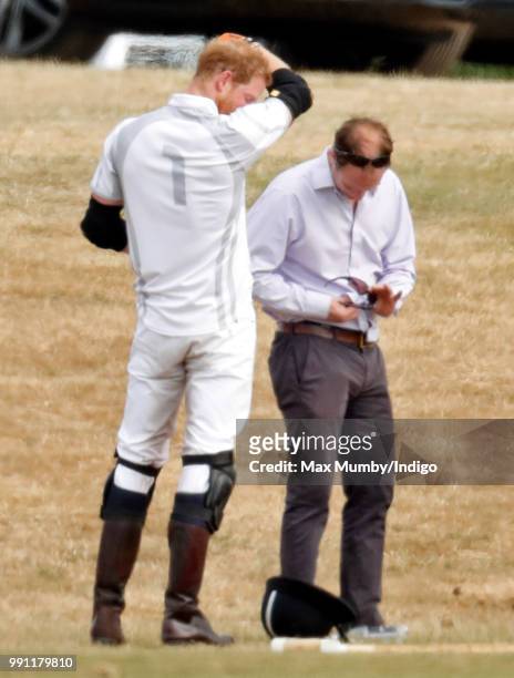 Prince Harry, Duke of Sussex looks on as he has his sunglasses cleaned for him by his polo manager Andrew Tucker during the Audi Polo Challenge at...