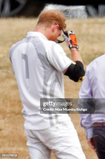 Prince Harry, Duke of Sussex puts on his sunglasses after having them cleaned by his polo manager Andrew Tucker during the Audi Polo Challenge at...