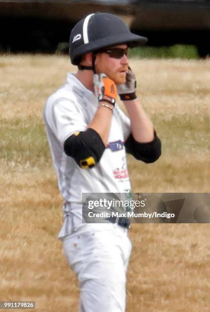 Prince Harry, Duke of Sussex puts on his helmet before taking part in the Audi Polo Challenge at Coworth Park Polo Club on July 1, 2018 in Ascot,...