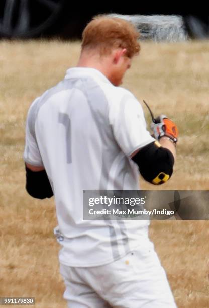 Prince Harry, Duke of Sussex puts on his sunglasses after having them cleaned by his polo manager Andrew Tucker during the Audi Polo Challenge at...