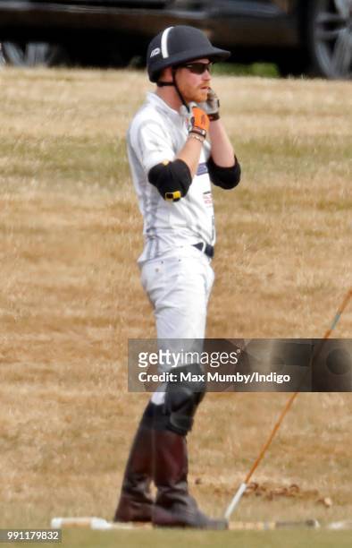 Prince Harry, Duke of Sussex puts on his helmet before taking part in the Audi Polo Challenge at Coworth Park Polo Club on July 1, 2018 in Ascot,...