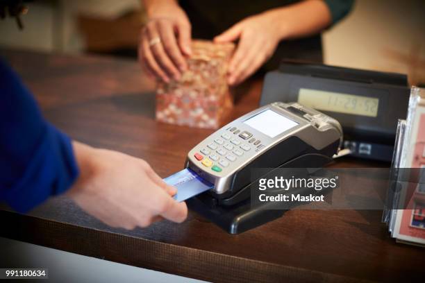 cropped image of customer paying through credit card at checkout counter - debit cards credit cards accepted stock pictures, royalty-free photos & images