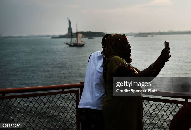 Couple enjoy the evening on the Staten Island Ferry as the Statue of Liberty stands in New York Harbor as America prepares to celebrate the 4th of...
